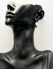 Pearl earring on a black mannequin bust with a white background