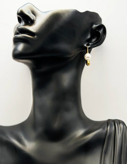 Pearl earring on a black mannequin bust with a white background