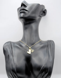 Waterproof non-tarnish gold heart jewelry resting on white silk fabric.