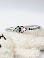 Silver ring with a heart-shaped gemstone on a white surface