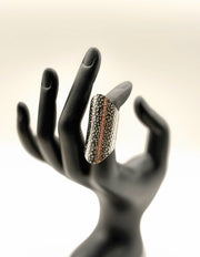 Decorative ring on a black mannequin hand against a light background