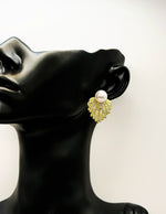 Close up of imitation jewelry uae statement earrings featuring a white pearl and gold crystal flare.