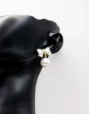 Close up of elegant imitation jewelry uae featuring an enamel ribbon stud and faux pearl drop.